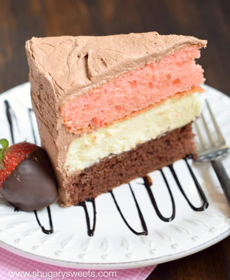 Neapolitan Cheesecake Cake: a layer of chocolate cake and a layer of strawberry cake with a cheesecake center. All wrapped in a fluffy chocolate buttercream frosting!