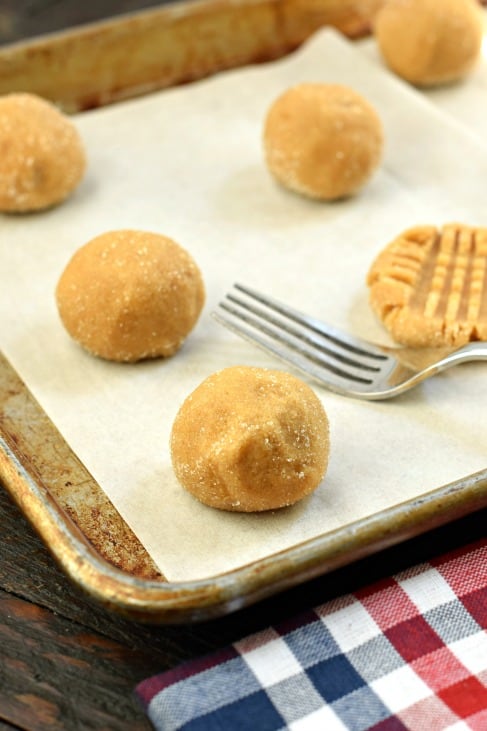 Peanut butter cookie dough rolled in granulated sugar and placed on a parchment paper lined baking sheet.