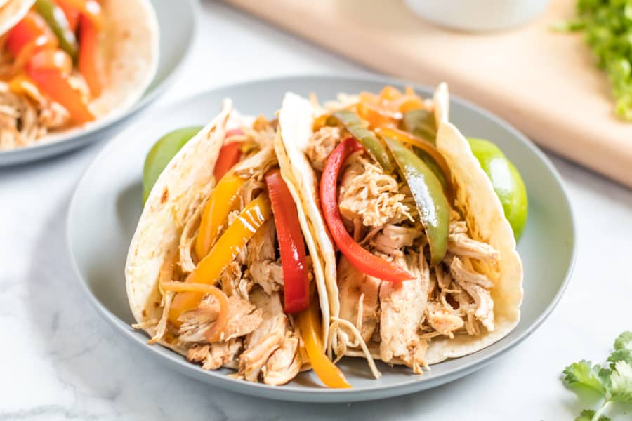 Chicken and sliced peppers on a flour tortilla on a gray plate.