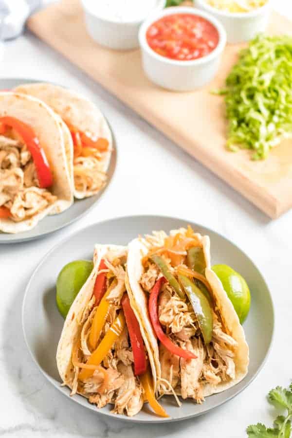 Two chicken fajitas on flour tortillas on a gray dinner plate.