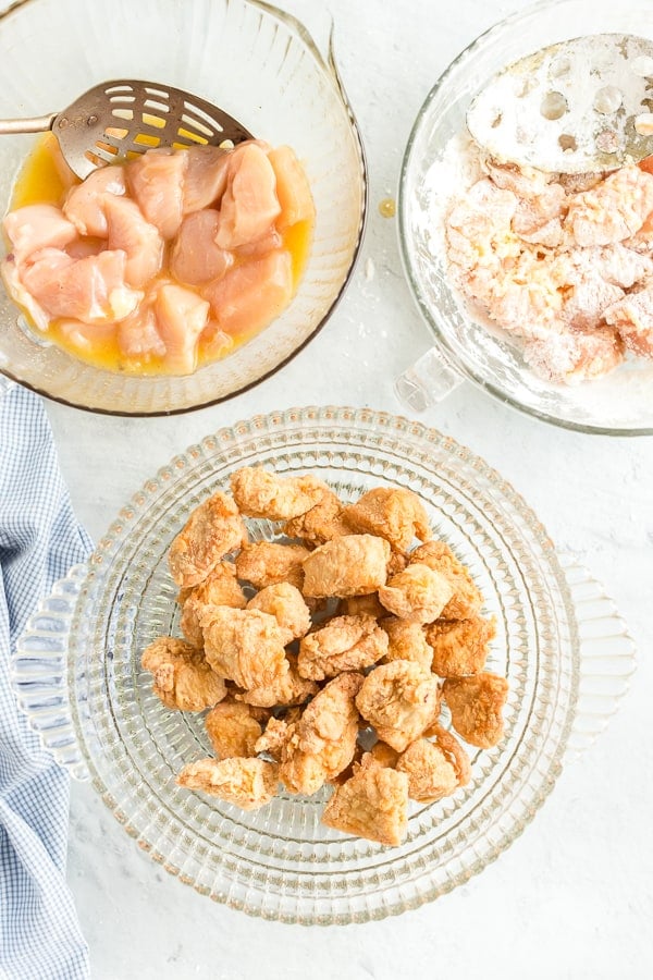 Prep bowls with chicken in egg mixture, chicken in flour mixture, and crispy chicken