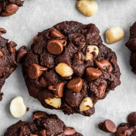 Chocolate macadamia nut cookies on a parchment paper lined cookie sheet.