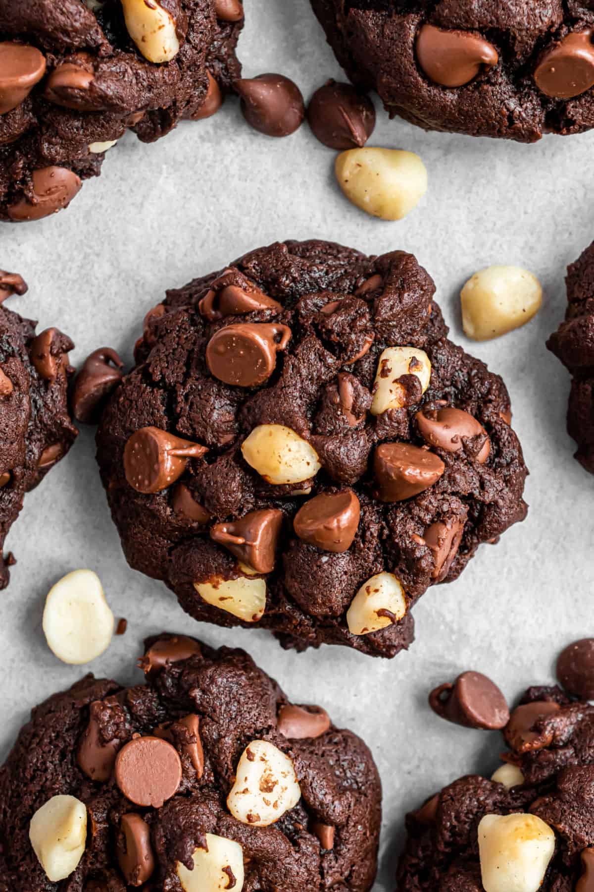 Chocolate macadamia nut cookies on a parchment paper lined cookie sheet.