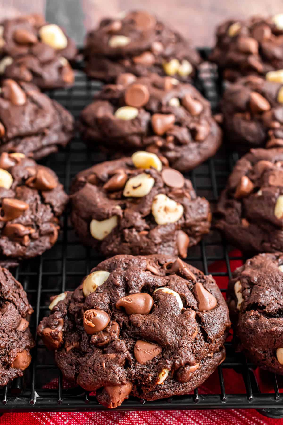 Chocolate macadamia nut cookies on a black wire cooling rack.