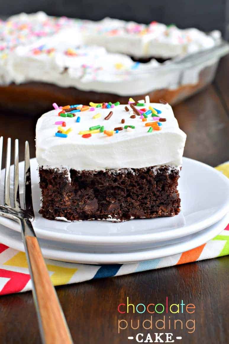 Tarta de chocolate densa con nata montada y chispitas en un plato de postre blanco.