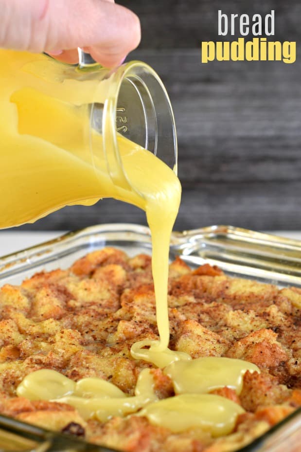 Lemon sauce being poured over baked warm bread pudding.