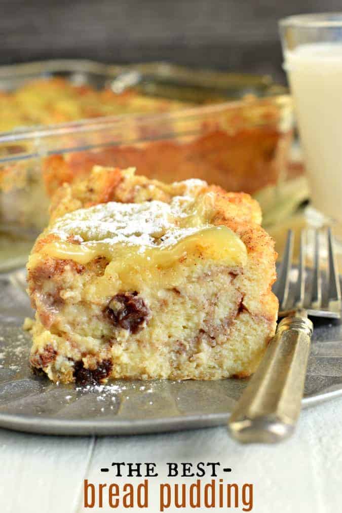 Thick slice of bread pudding topped with lemon sauce and powdered sugar on a dessert plate.