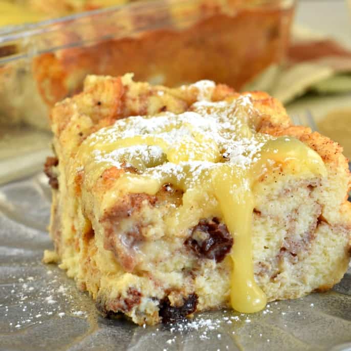 Close up of bread pudding dripping with lemon sauce on a silver plate.