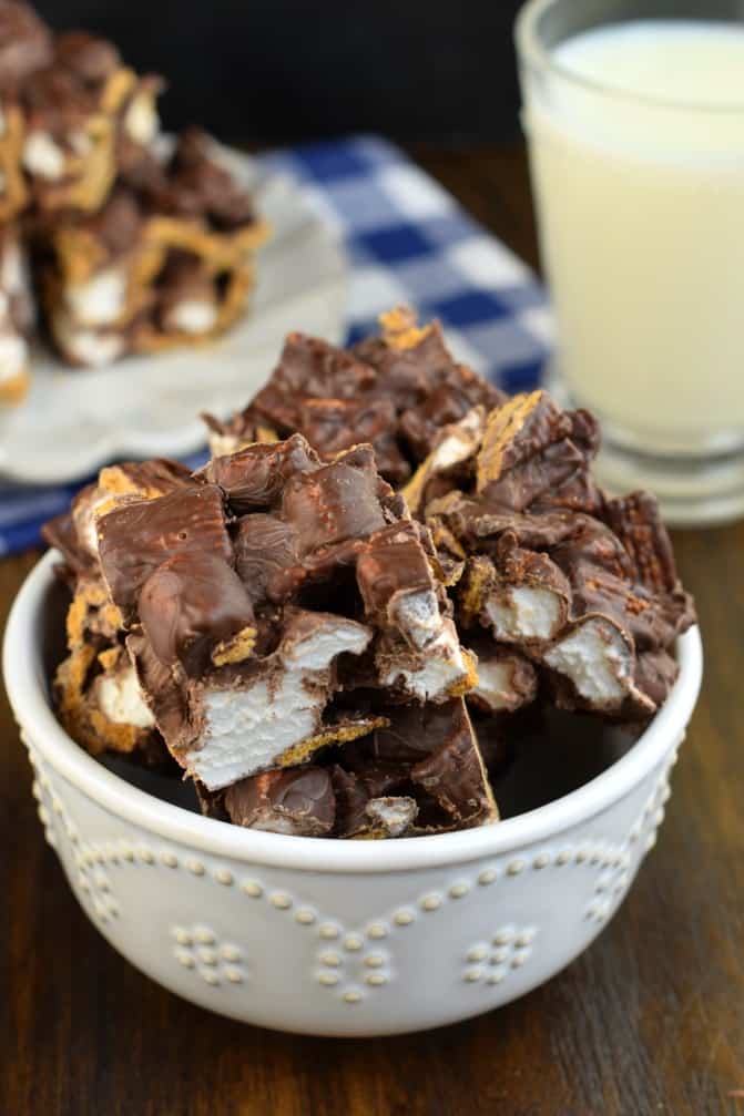 Chocolate, golden graham cereal, and marshmallow squares in a small white bowl.