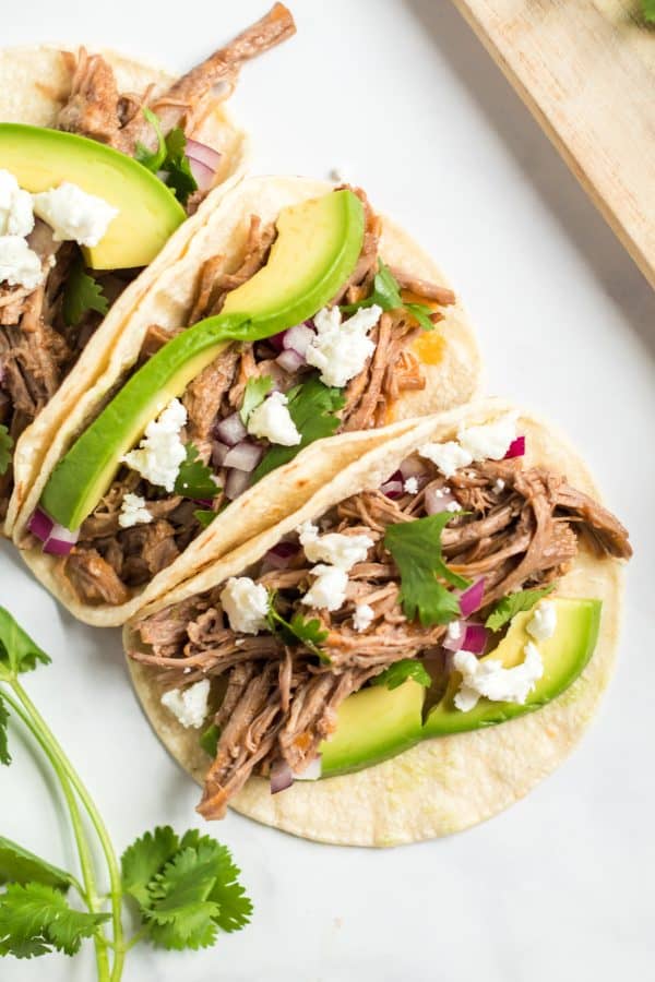 Cotija cheese, avocado, red onion, and barbacoa beef on a tortilla.