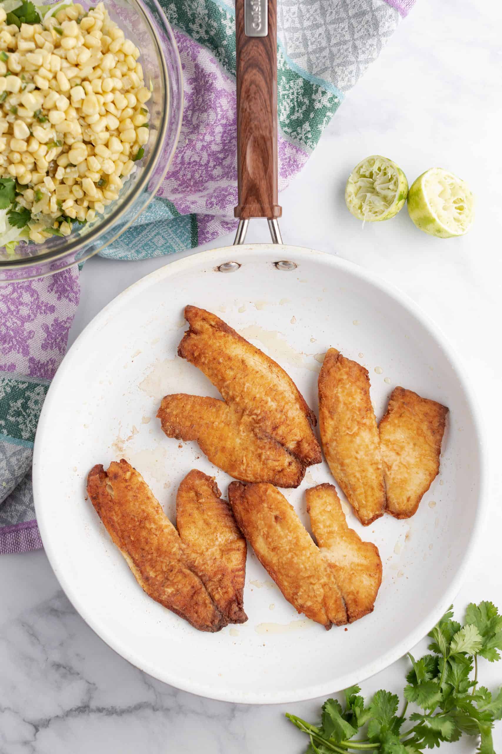 Cooked fish on a white plate ready to be added to tacos.