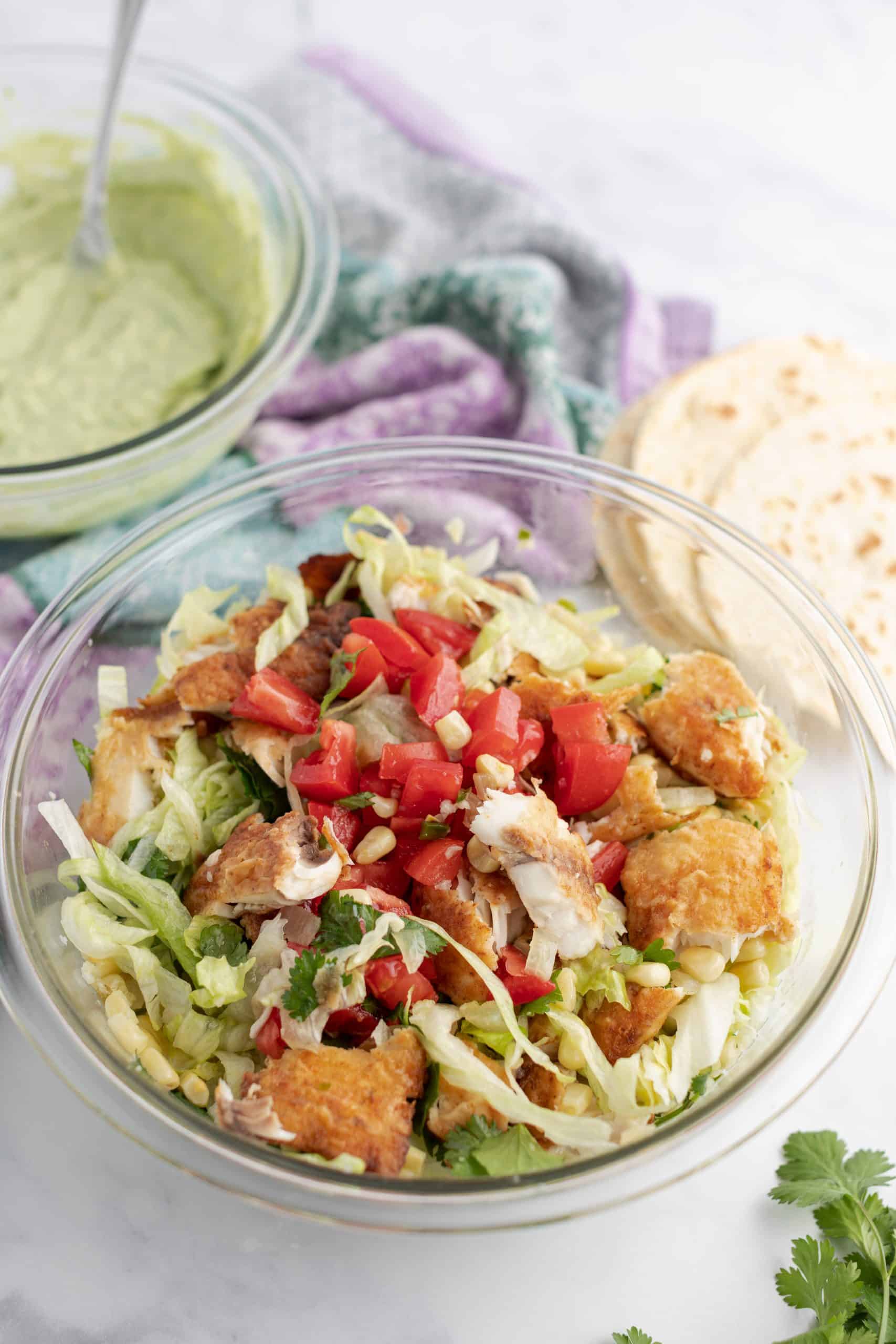 Clear glass bowl with all the fixings for fish tacos.