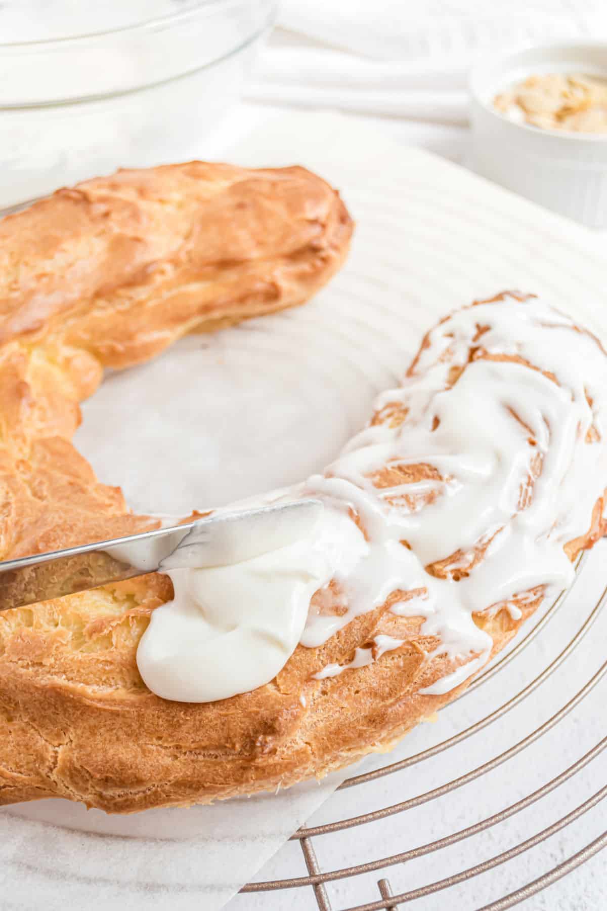 Almond icing being spread over a homemade kringle.