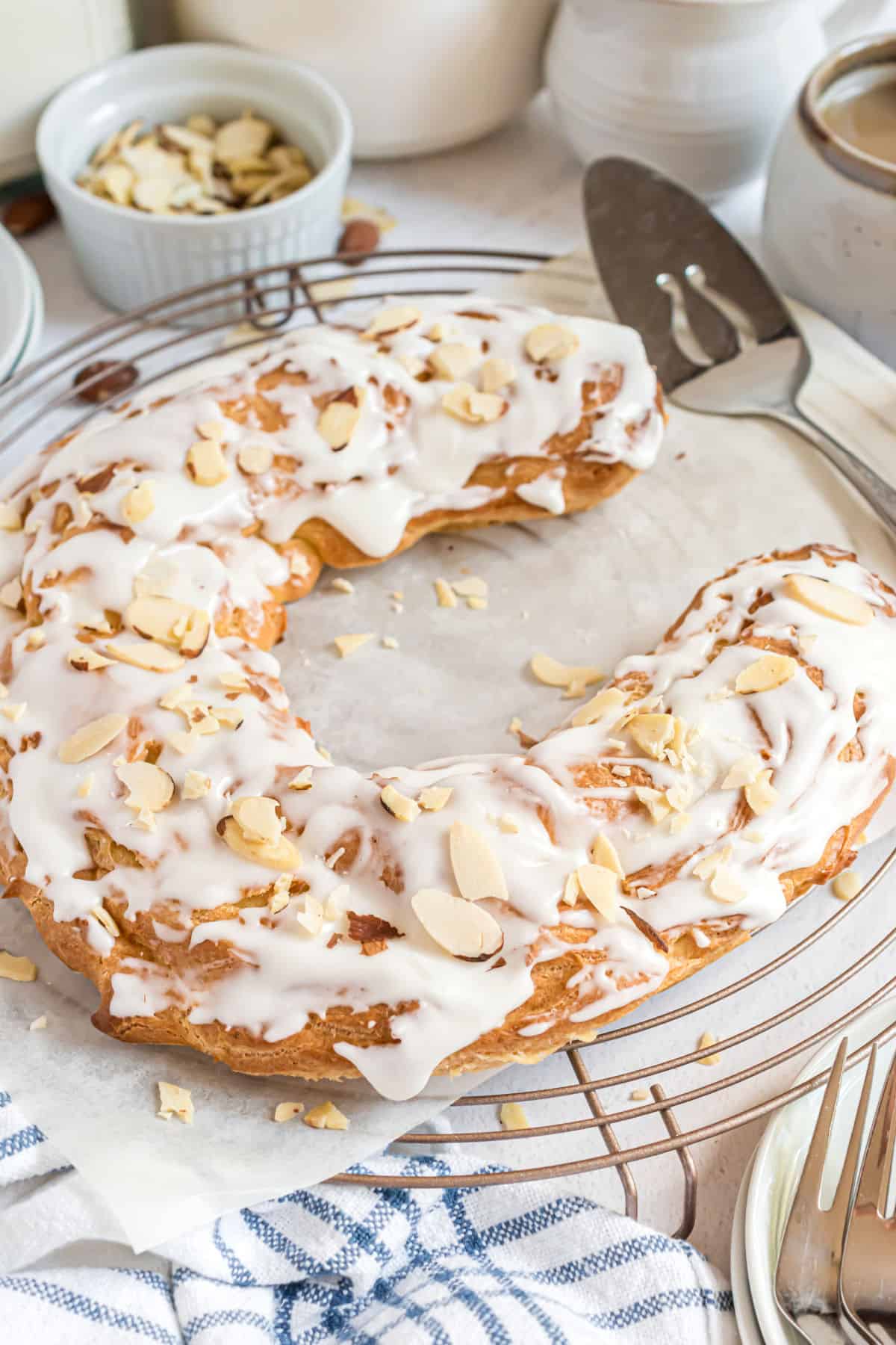 Almond kringle with icing on a wire rack to serve.