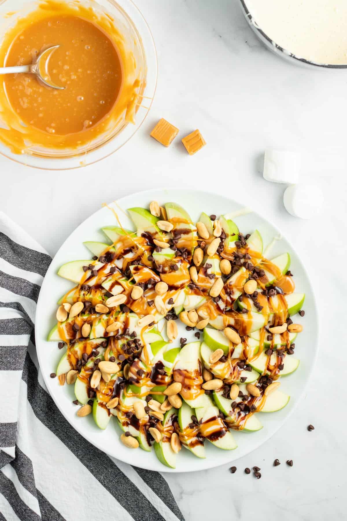 Plate of apple slices topped with melted caramel, marshmallow and chocolate.