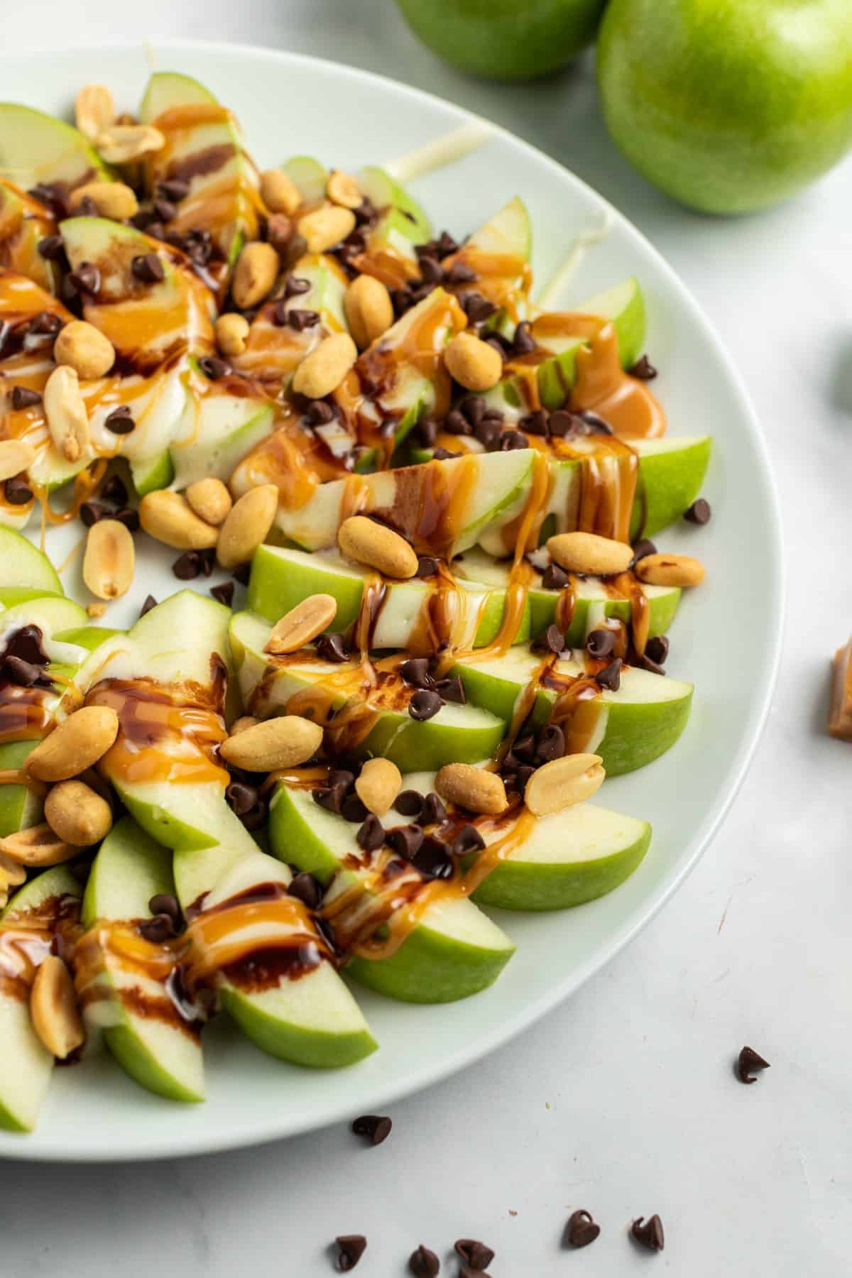 Apple nachos on a plate with green apple slices, caramel, chocolate, and melted marshmallow.