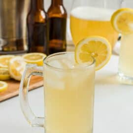 Beer mug with homemade summer shandy, garnished with a lemon slice.