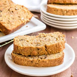 Two slices of zucchini bread with walnuts, carrots, and pineapple on a white plate.