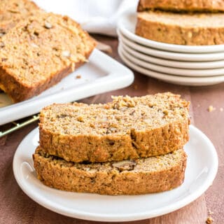 Two slices of zucchini bread with walnuts, carrots, and pineapple on a white plate.