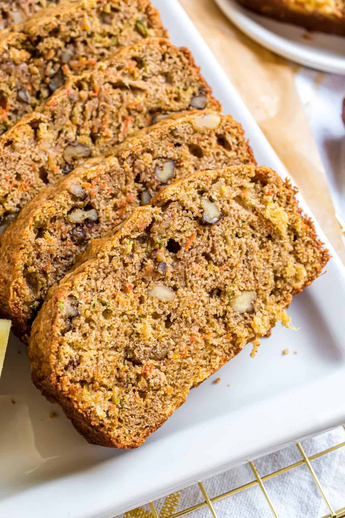 Sliced pineapple carrot zucchini bread with walnuts on a white plate.