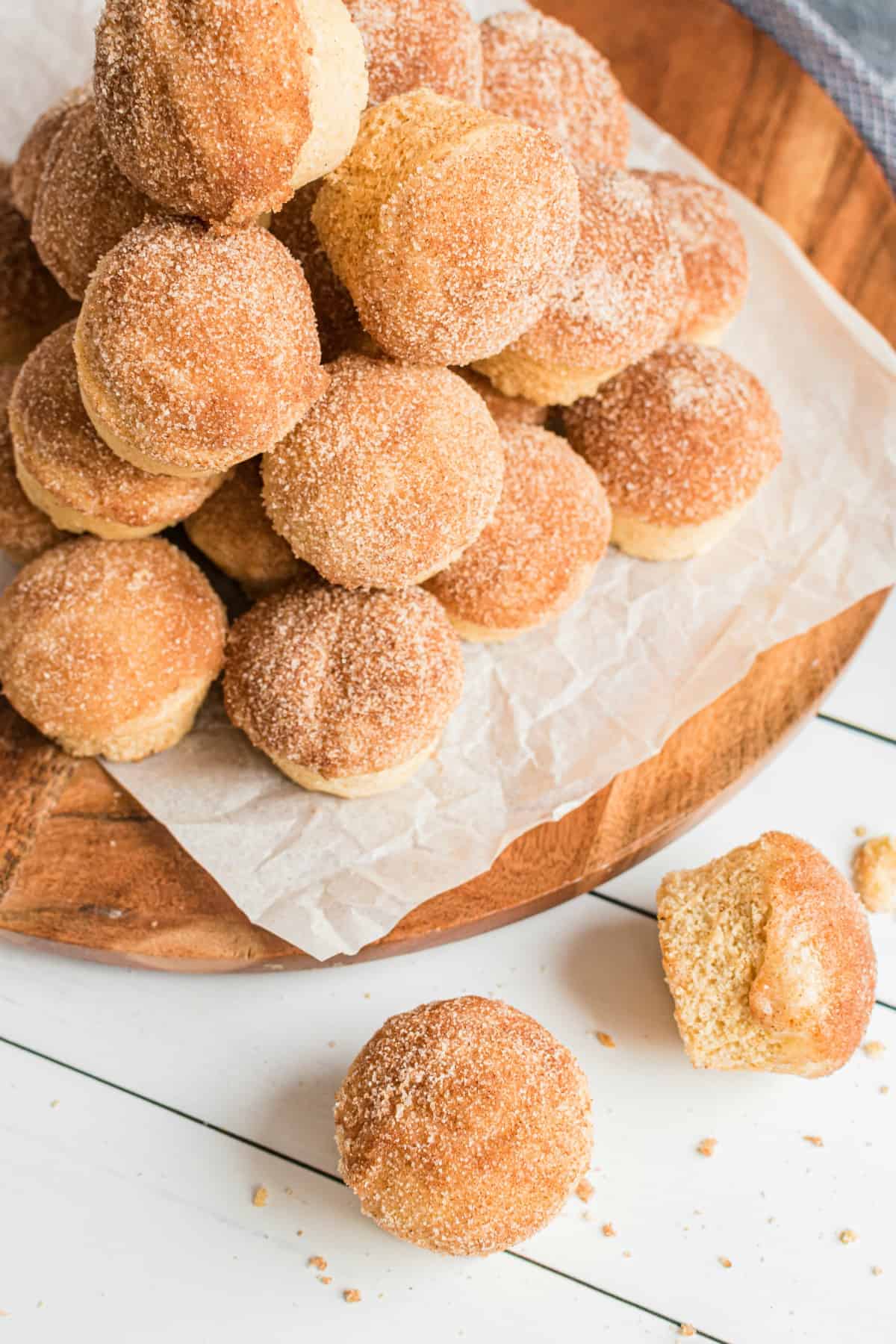 Wooden board topped with parchment paper and a stack of cinnamon muffins.