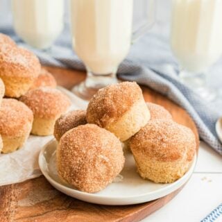 Cinnamon muffins on a white plate with a stack of muffins in background.