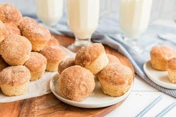 Cinnamon muffins on a white plate with a stack of muffins in background.