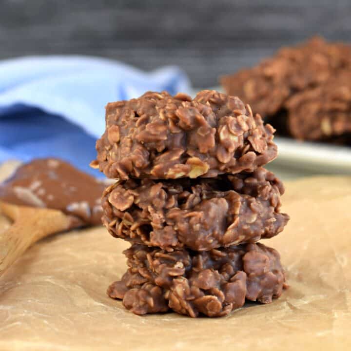 Stack of 3 chocolate, nutella, peanut butter, oatmeal no bake cookies on a piece of parchment paper.