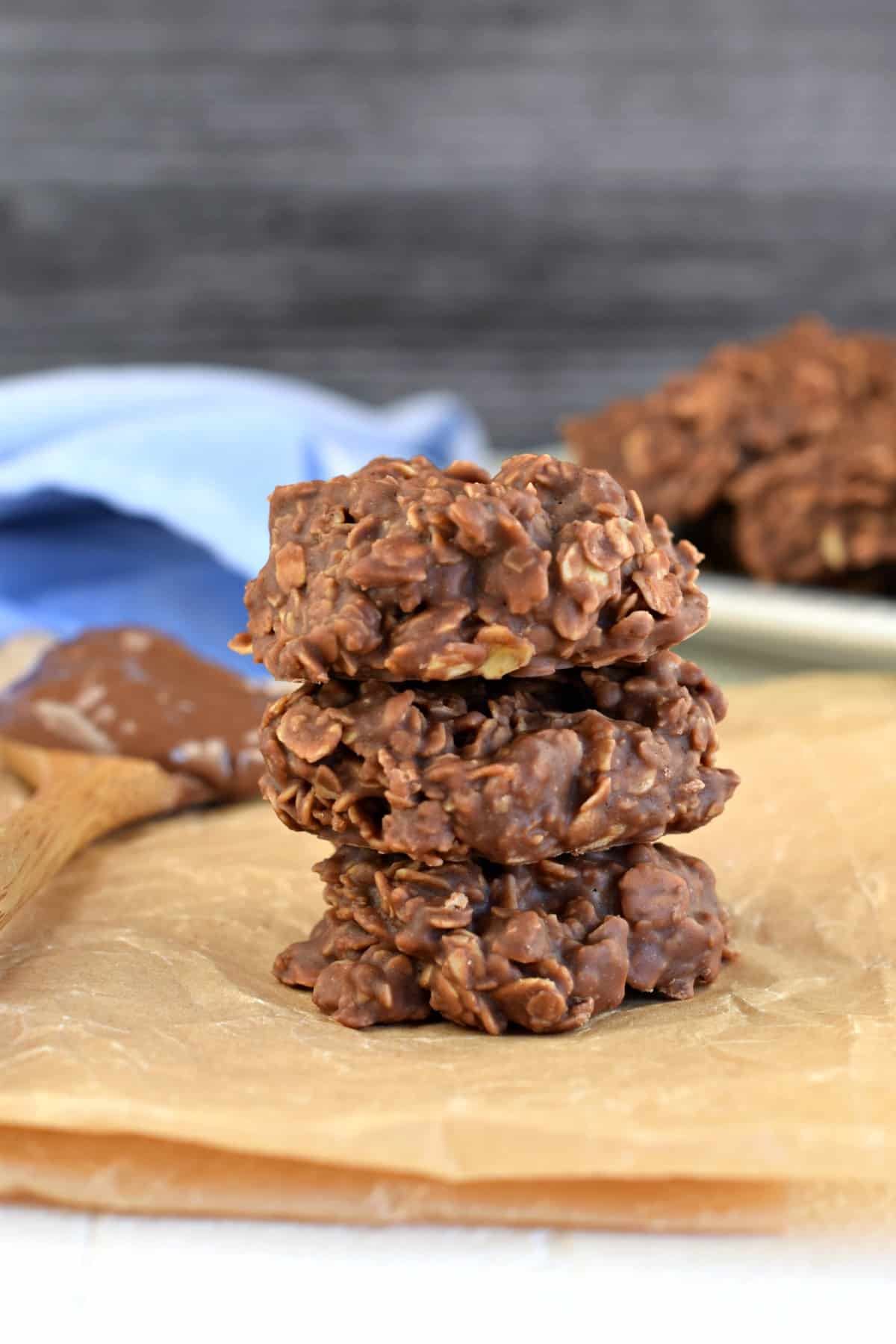 Stack of 3 chocolate, nutella, peanut butter, oatmeal no bake cookies on a piece of parchment paper.