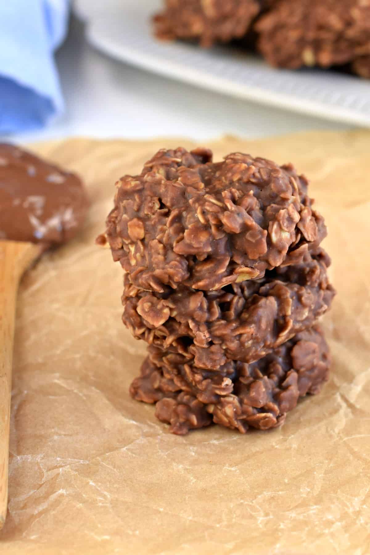 Stack of three nutella cookies on a piece of parchment paper with a small wooden spoon topped with nutella.