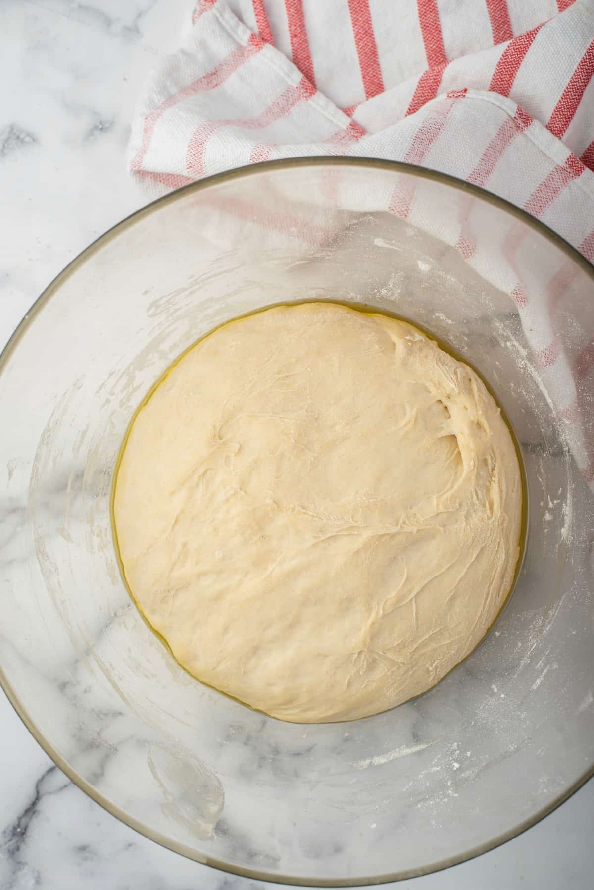 Glass bowl with yeast dough for breadstick recipe.
