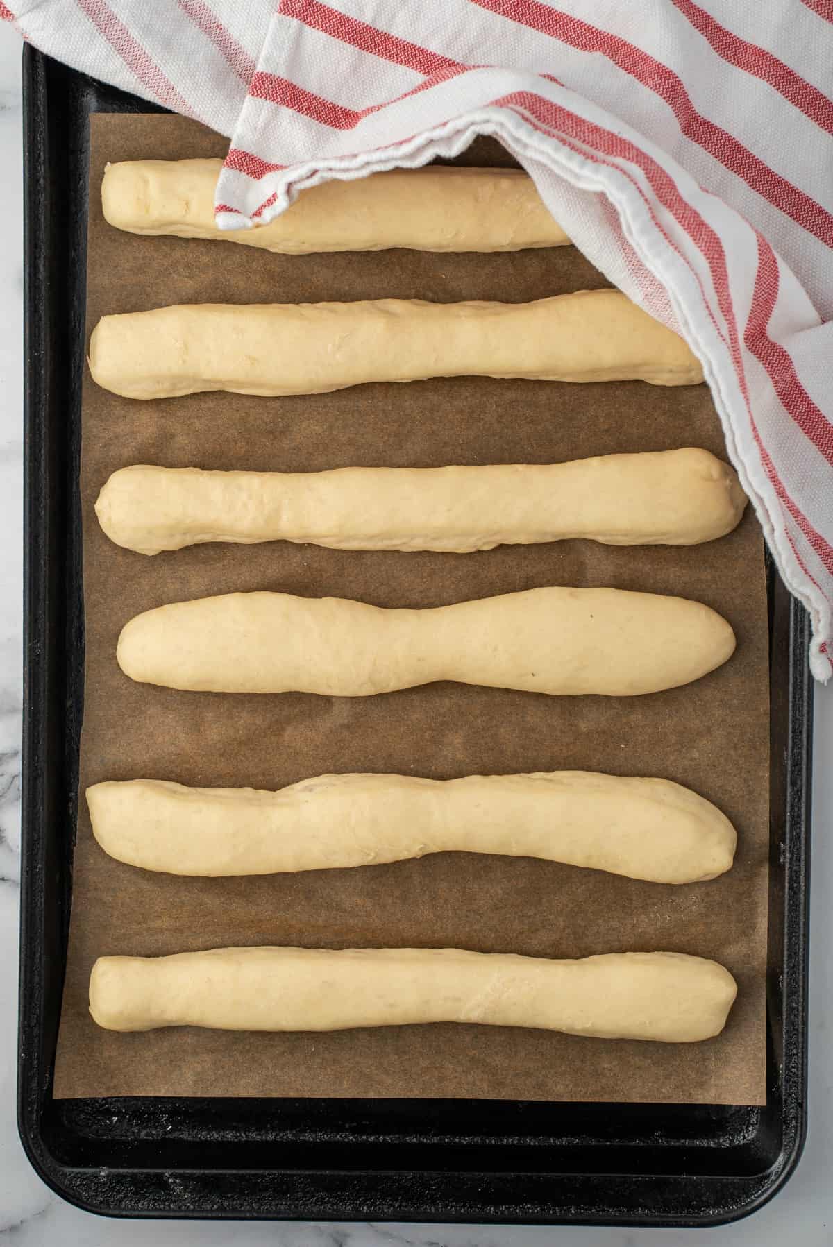Dough shaped into breadsticks on a baking sheet prior to baking.