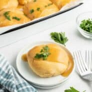 Chicken kisses in a 13x9 baking dish with one removed and placed on a white dinner plate. Topped with gravy and parsley.
