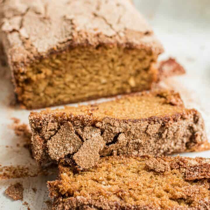 Loaf of cinnamon sugar crusted amish friendship bread on a white platter with a few slices cut.