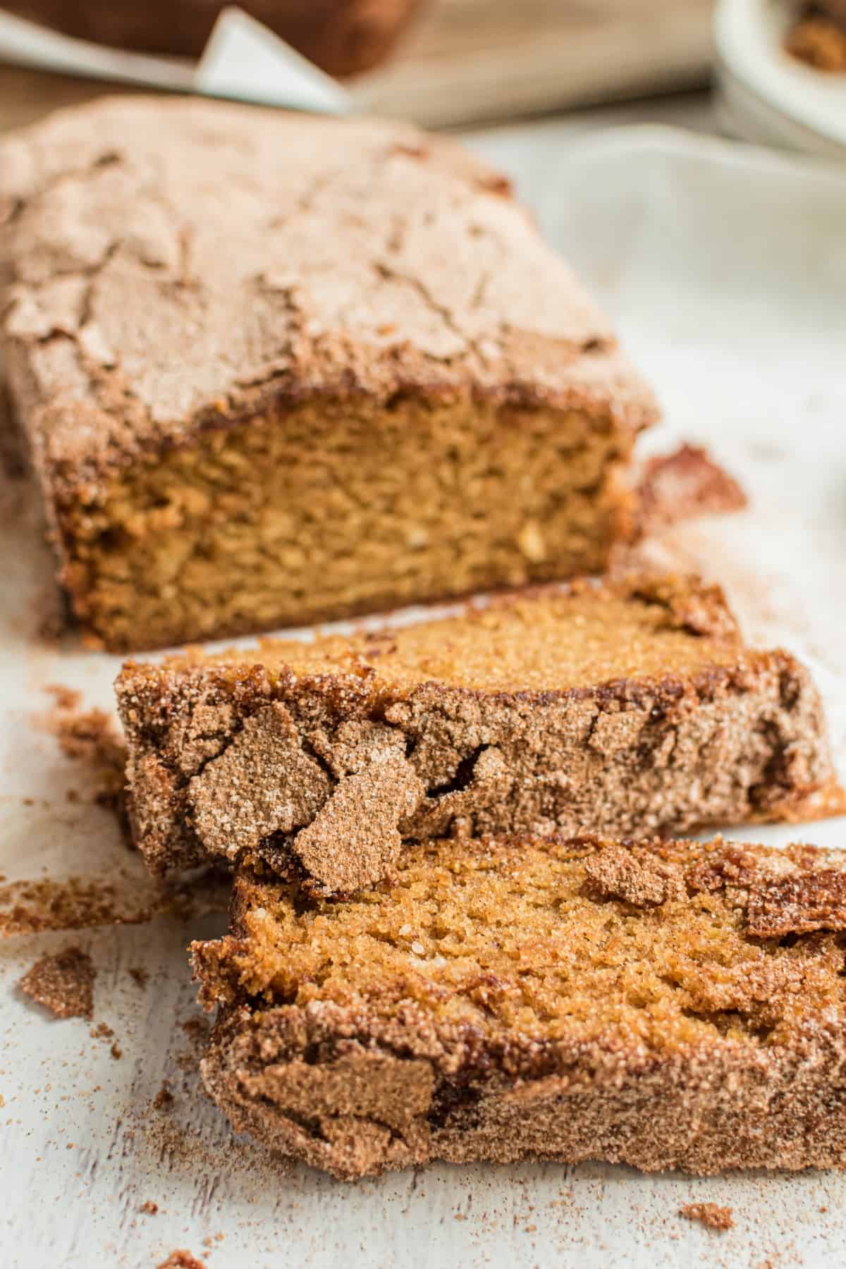 Loaf of cinnamon sugar crusted amish friendship bread on a white platter with a few slices cut.