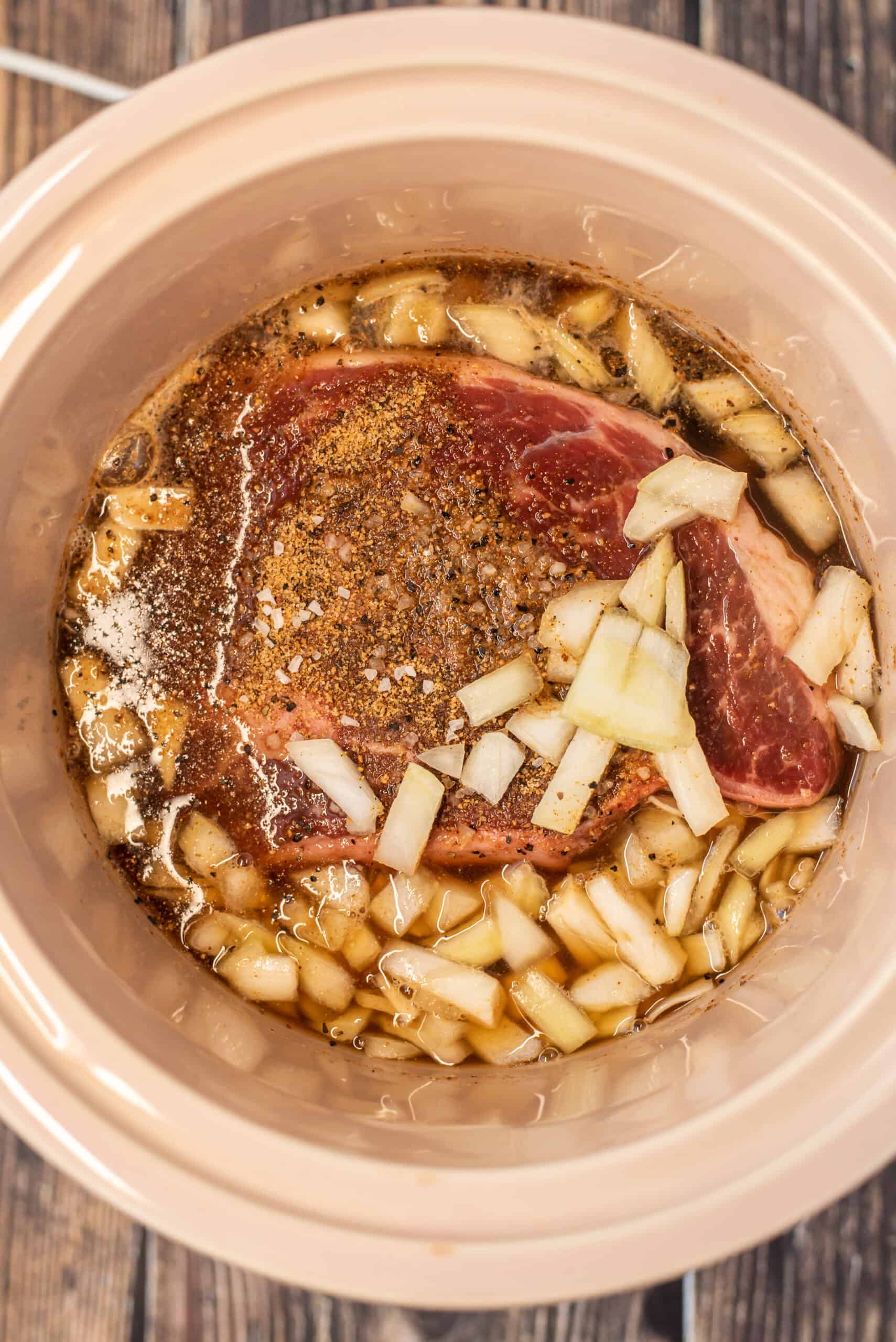Chuck roast with ingredients to make french dip in a crock pot.