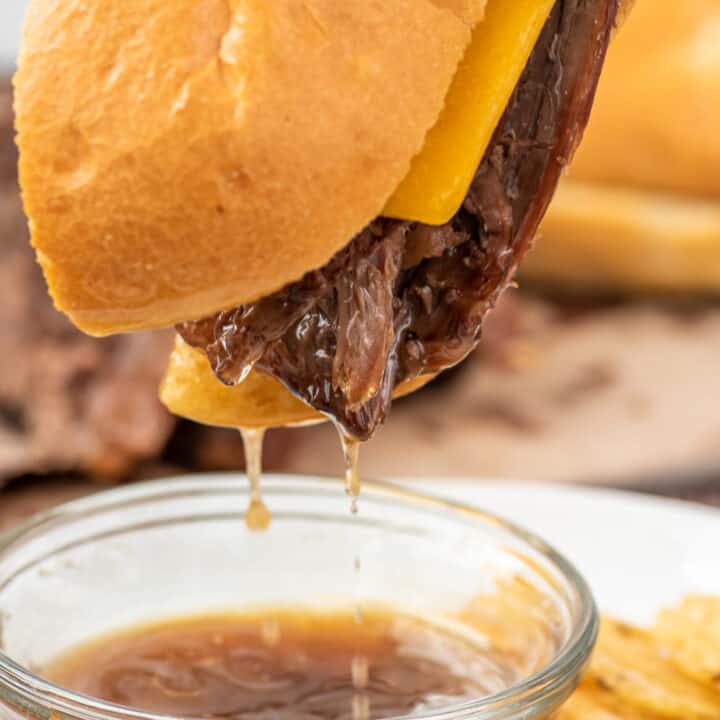 French Dip sandwich being dunked into au jus.