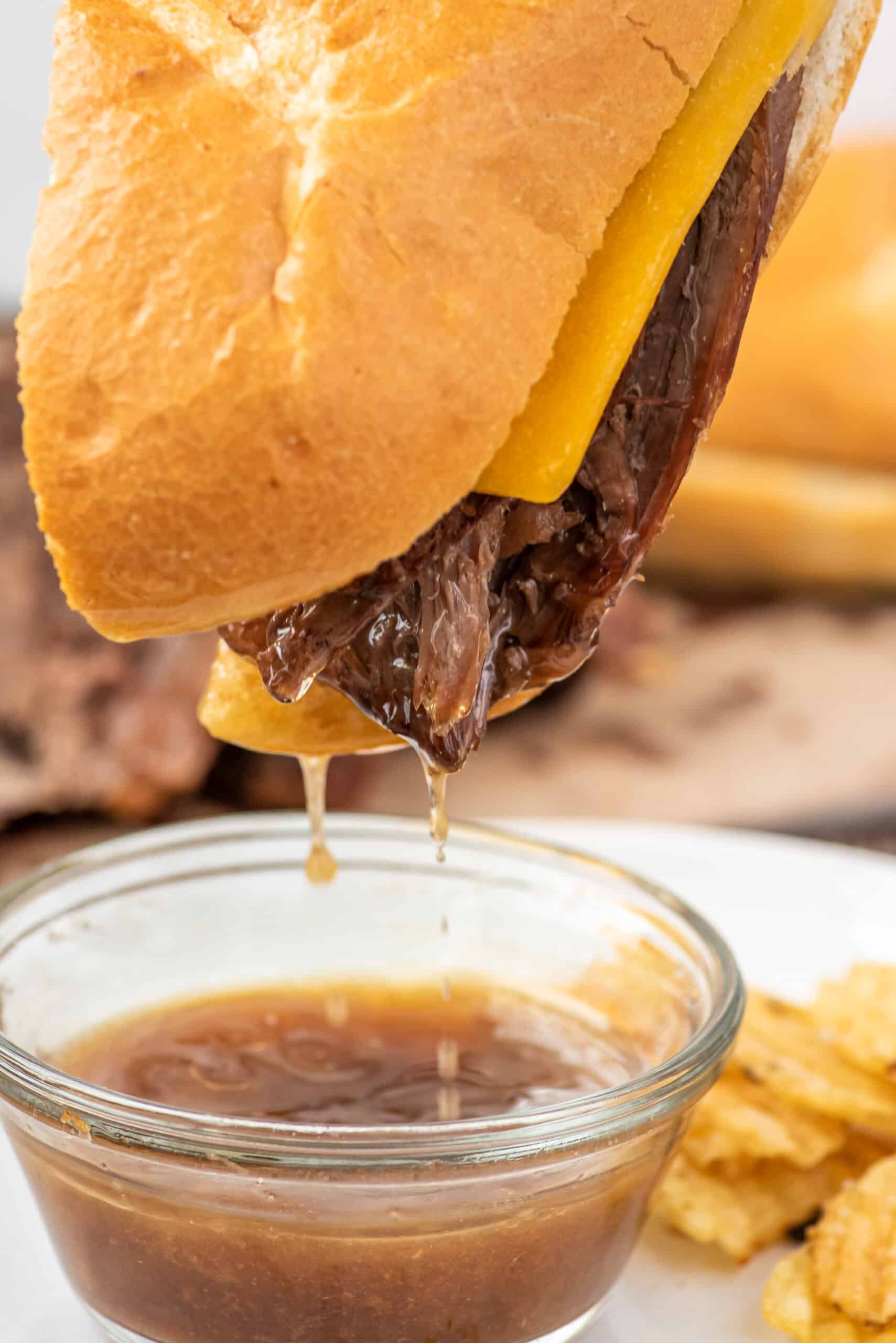 French Dip sandwich being dunked into au jus.