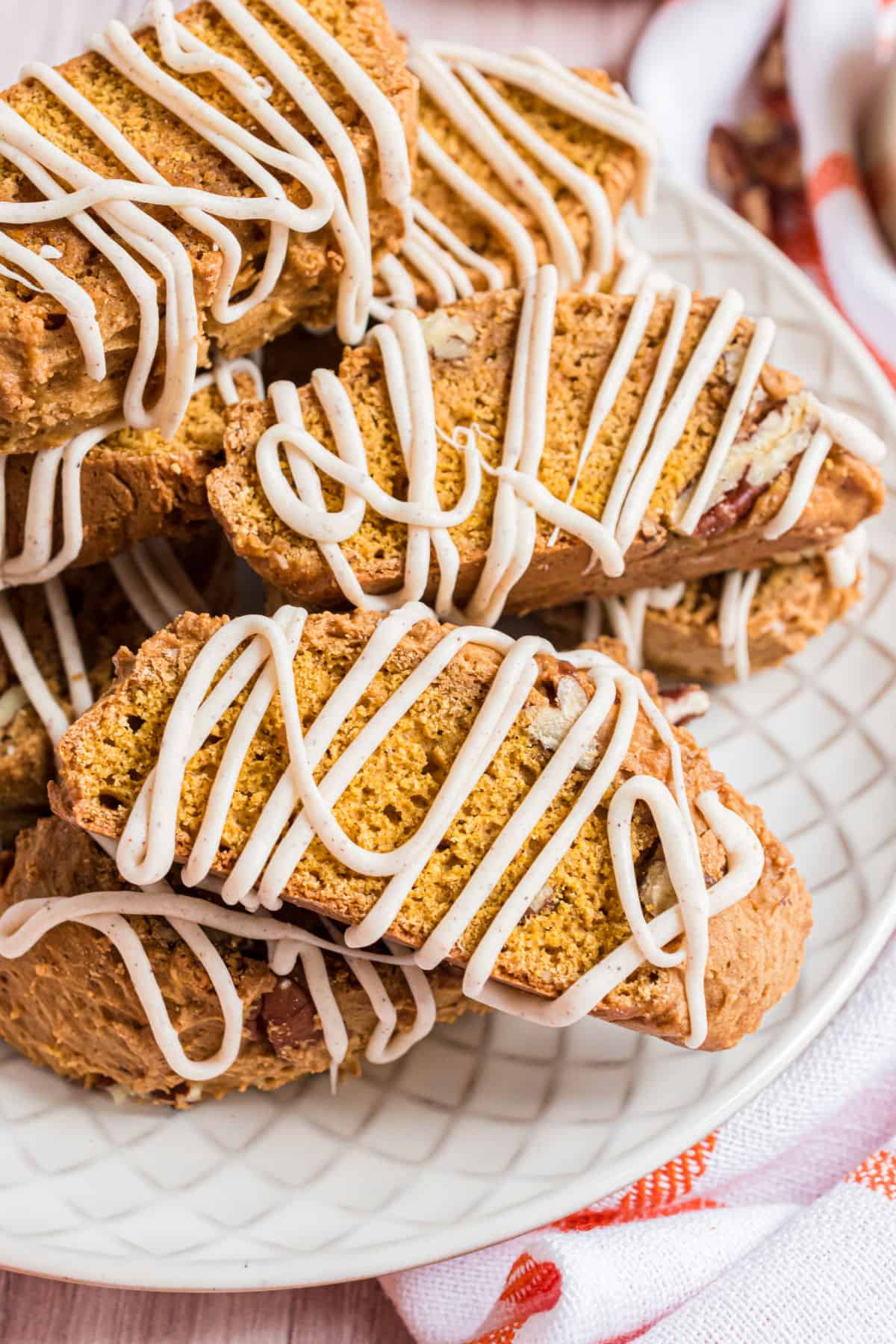 Pumpkin biscotti stacked on a white plate to serve.