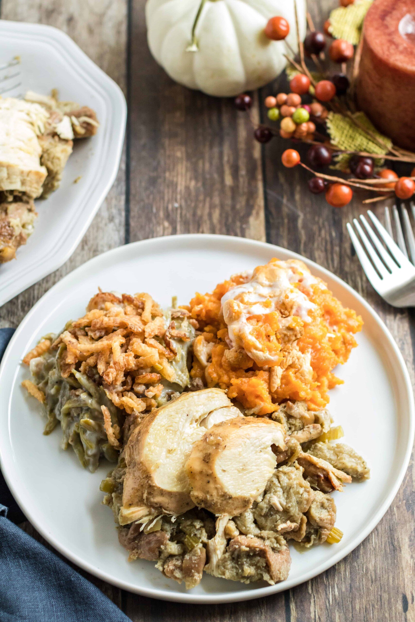 Dinner plate with a scoop of turkey and stuffing with sweet potato casserole and green bean casserole.