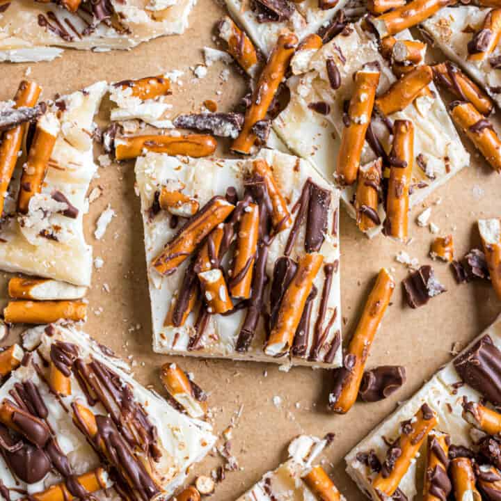 Pieces of white chocolate candy with salted caramel, pretzels, and milk chocolate drizzled on top.