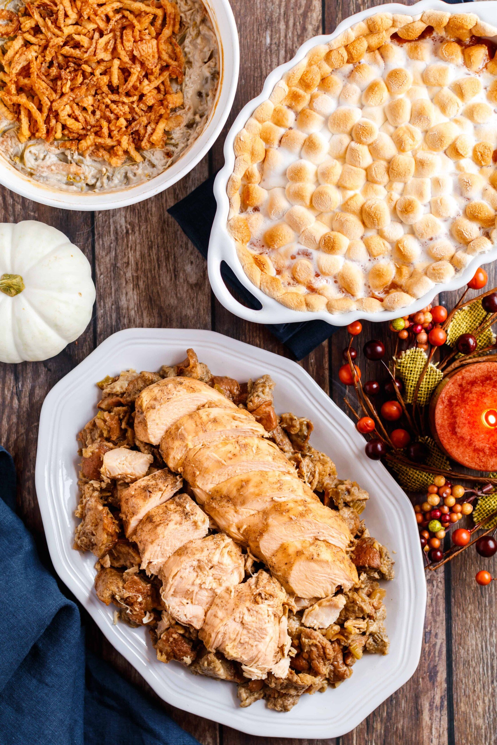 Plate of stuffing topped with sliced turkey breast on a thanksgiving table.