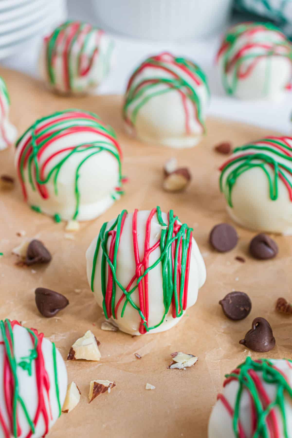 Almond truffles on wooden board with red and green chocolate drizzle.