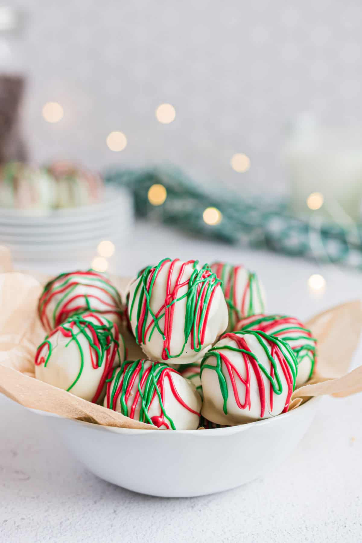 Almond truffles in white bowl with christmas lights in background.