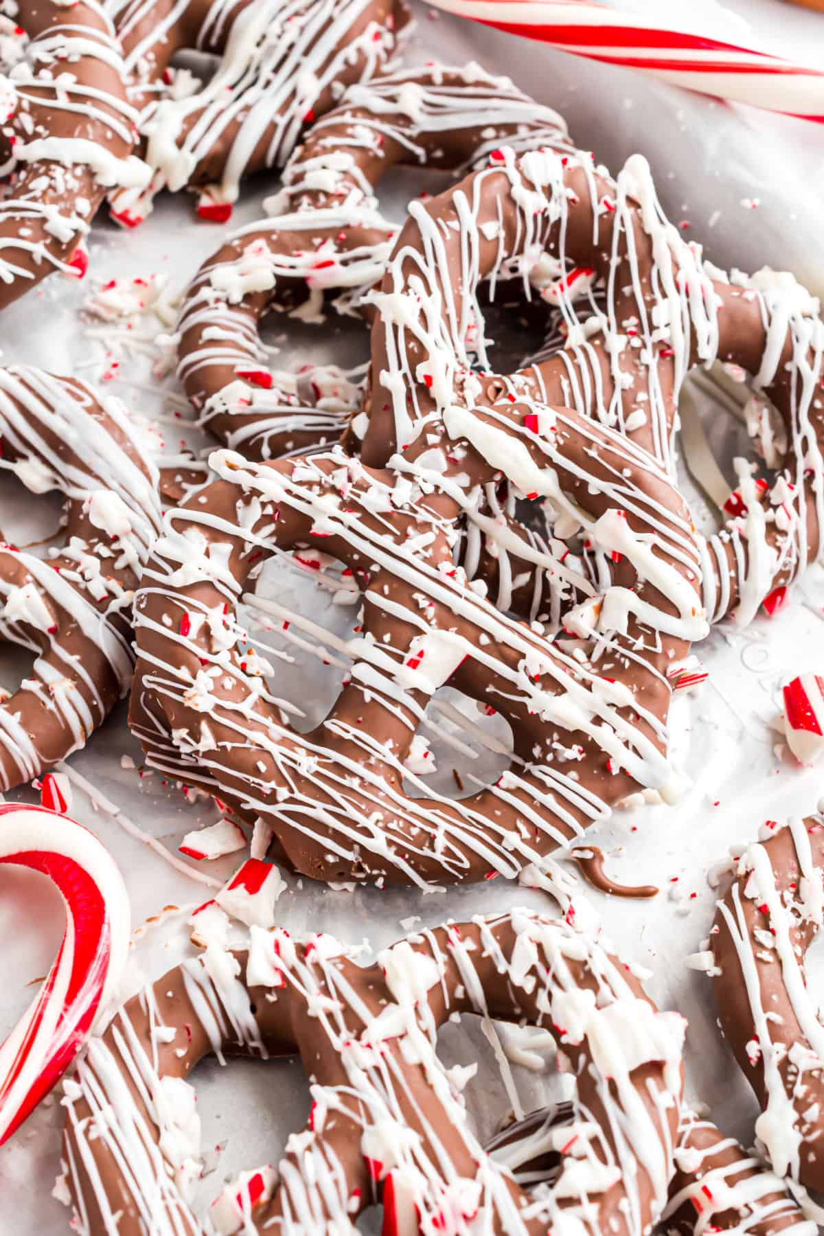 Stacks of chocolate covered peppermint pretzels on parchment paper.