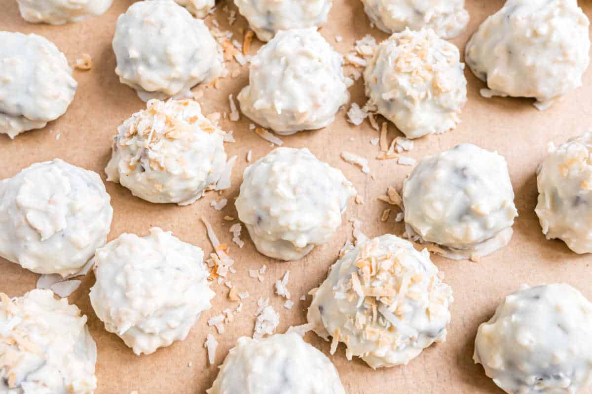 White chocolate and coconut covered truffles on parchment paper.