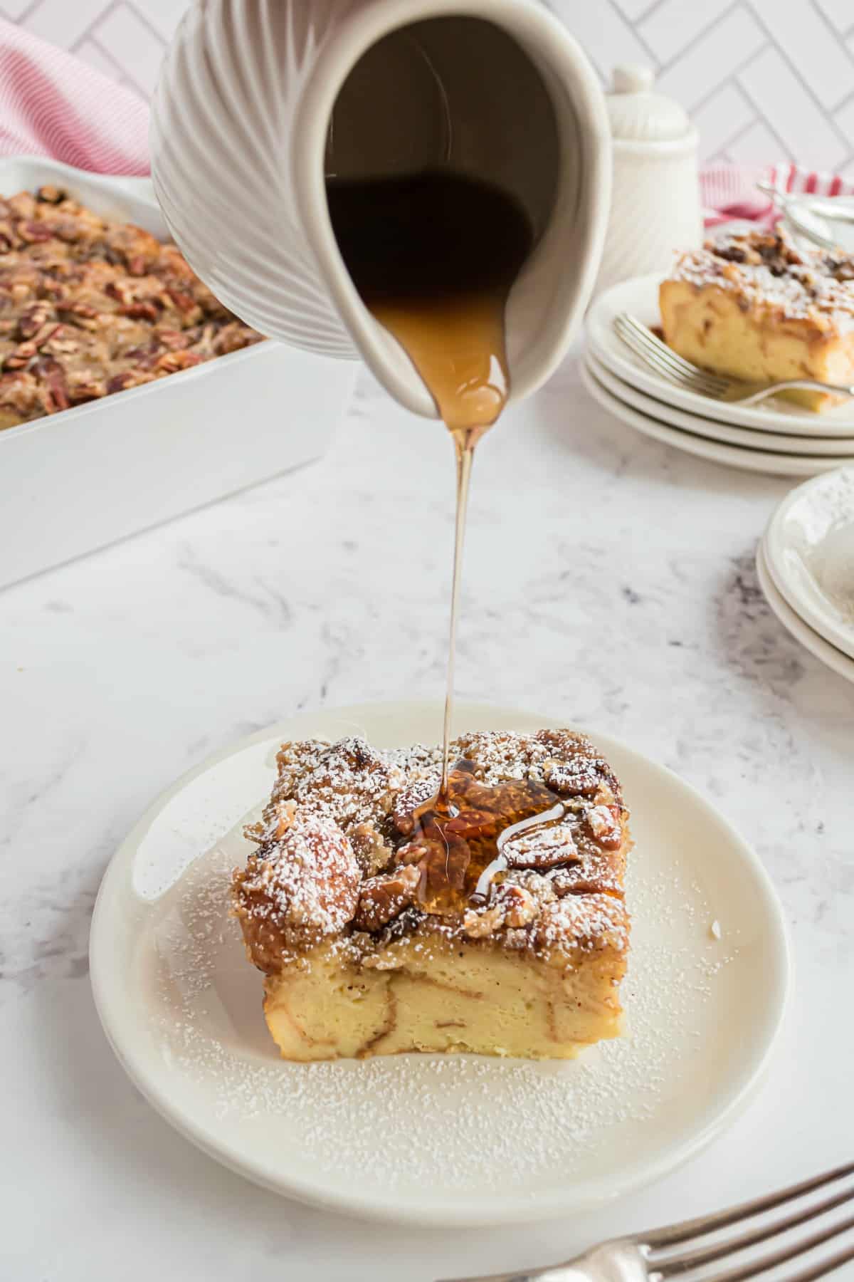 Maple syrup poured over a slice of eggnog french toast casserole.