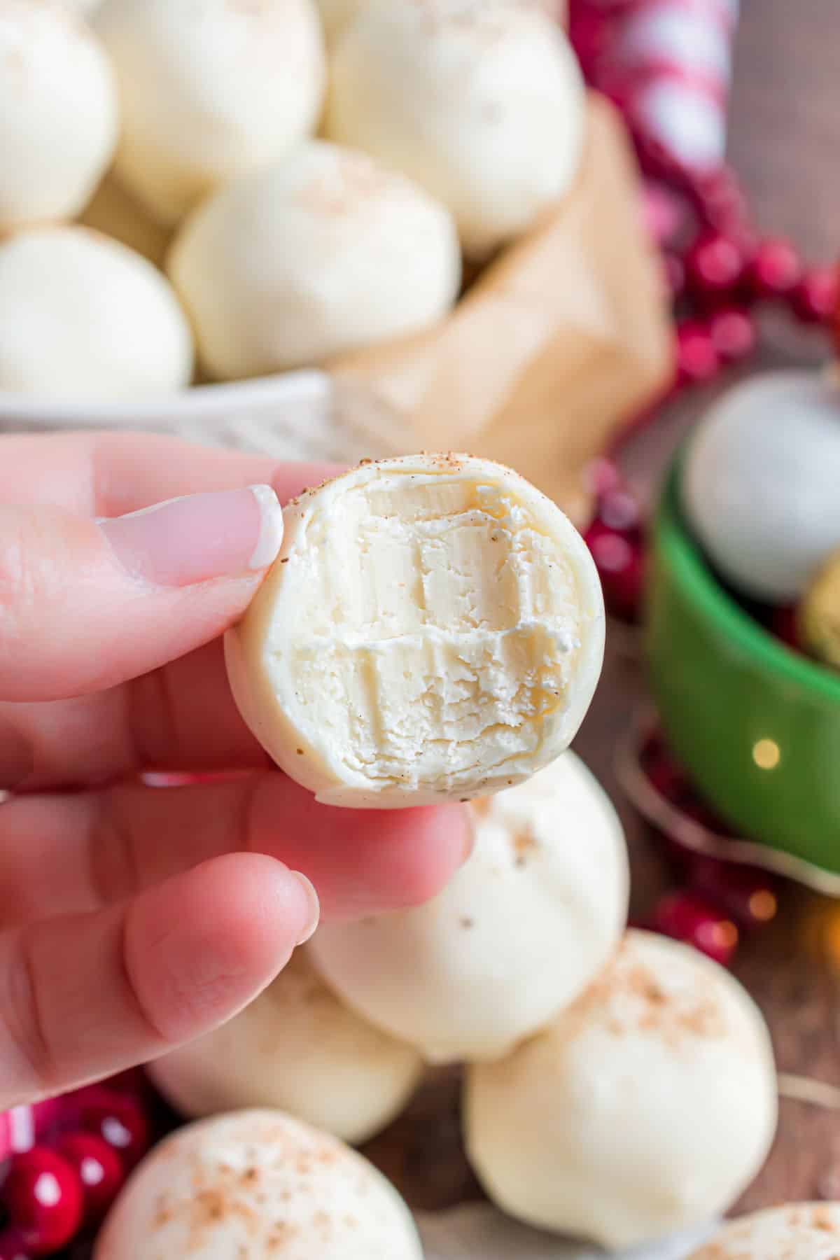 Bowl of eggnog truffles, one piece with a bite removed.