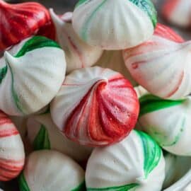 Red and green mint meringue cookies in a white bowl.