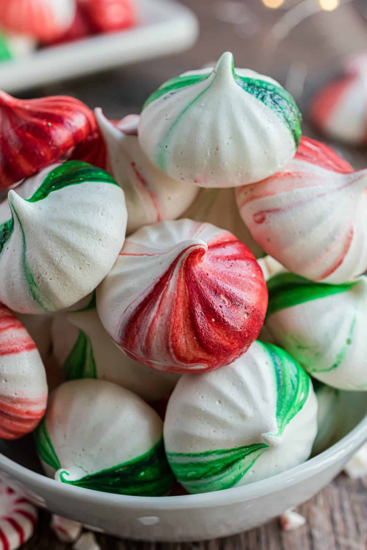 Red and green mint meringue cookies in a white bowl.